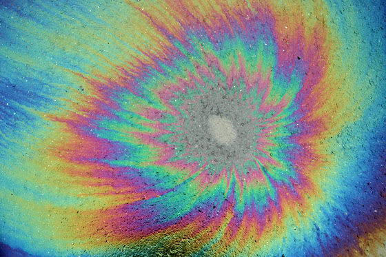 This is an image of an oil slick where there are circular rings of different colors. This is because the are differences in thickness in the oil slick and some interference between the other waves that are refracted that results in the perception of different colors. 