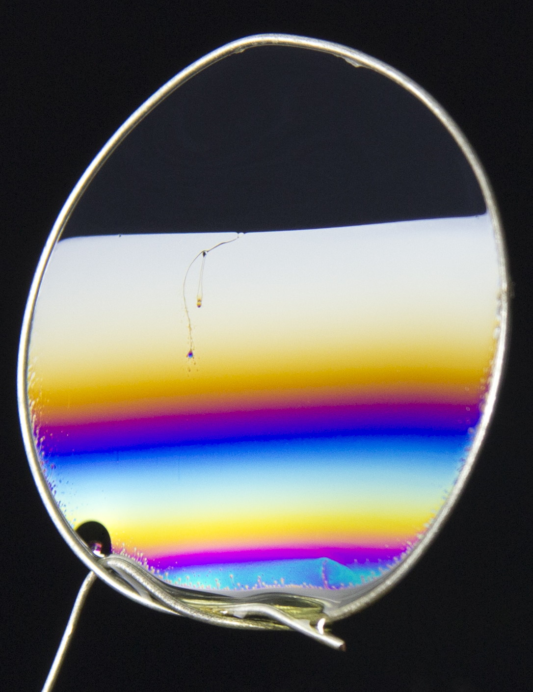 This is an image of a bubble with some material in it. There are different bands of colors because the refracted waves have different wavelengths and have some interference between the other waves that are refracted that results in the perception of different colors. 